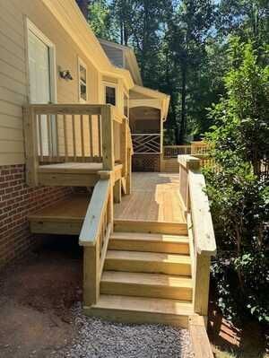 A wooden deck with stairs leading up to it and a screened in porch.