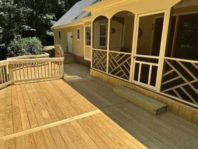 A screened in porch with a wooden deck in front of a house.