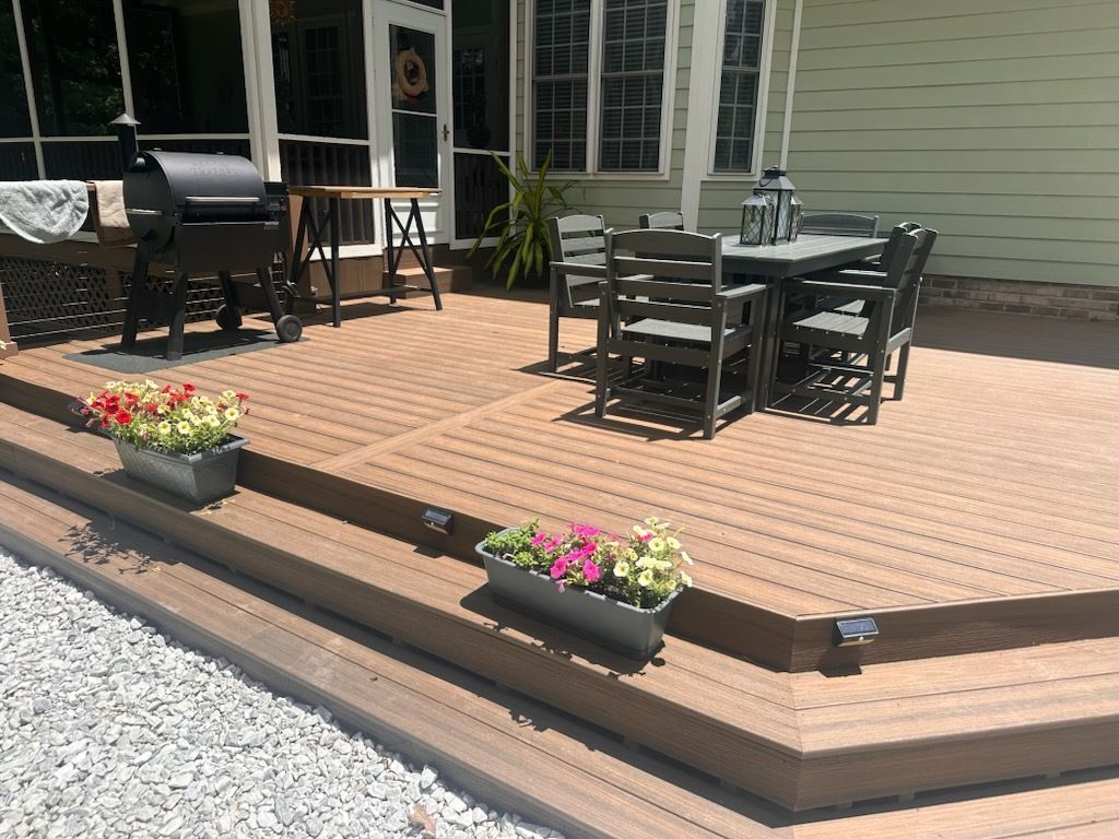 Composite deck with outdoor dining set, grill, and potted flowers.