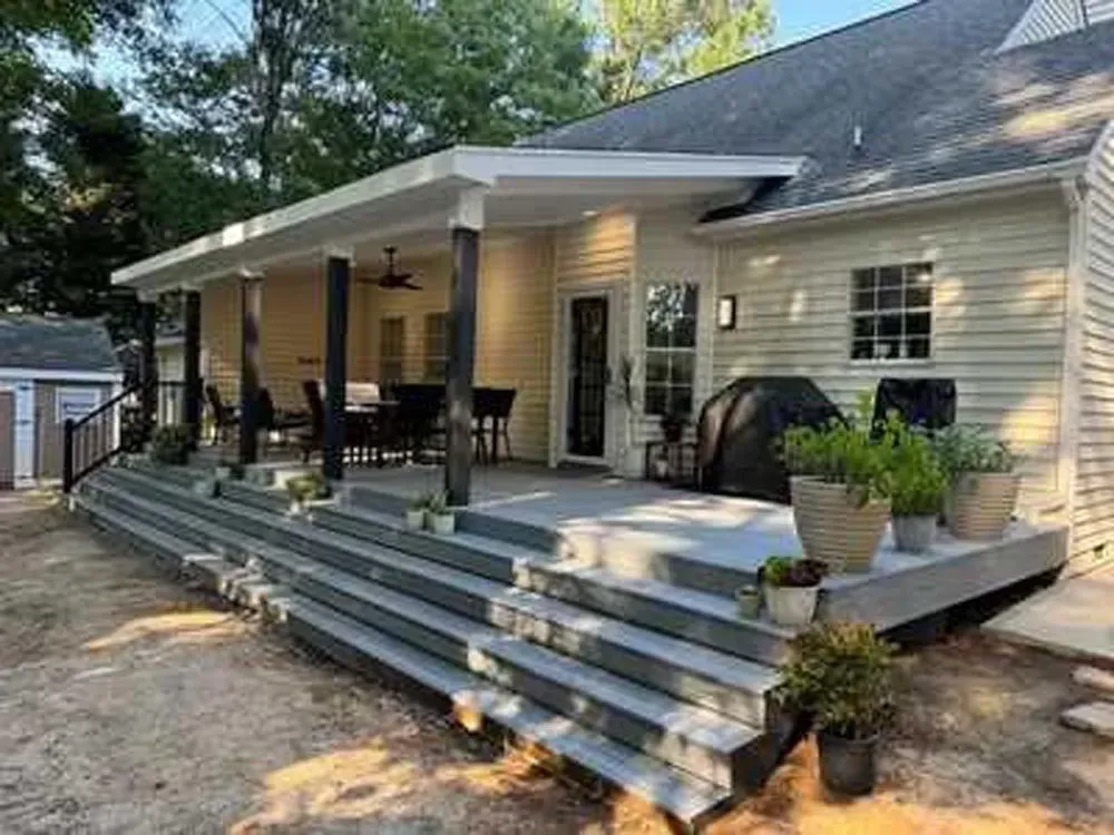 The back of a house with a large porch and stairs leading up to it.