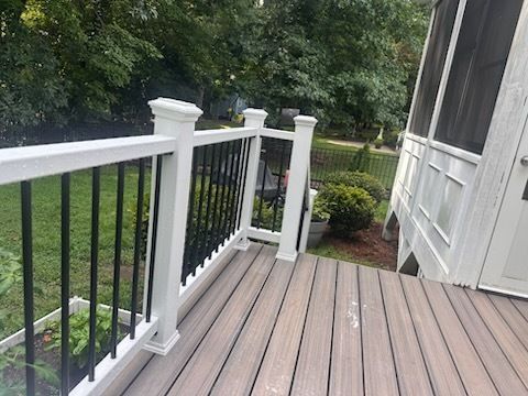 Deck with brown composite boards, white railing posts, black spindles, and a screened porch.