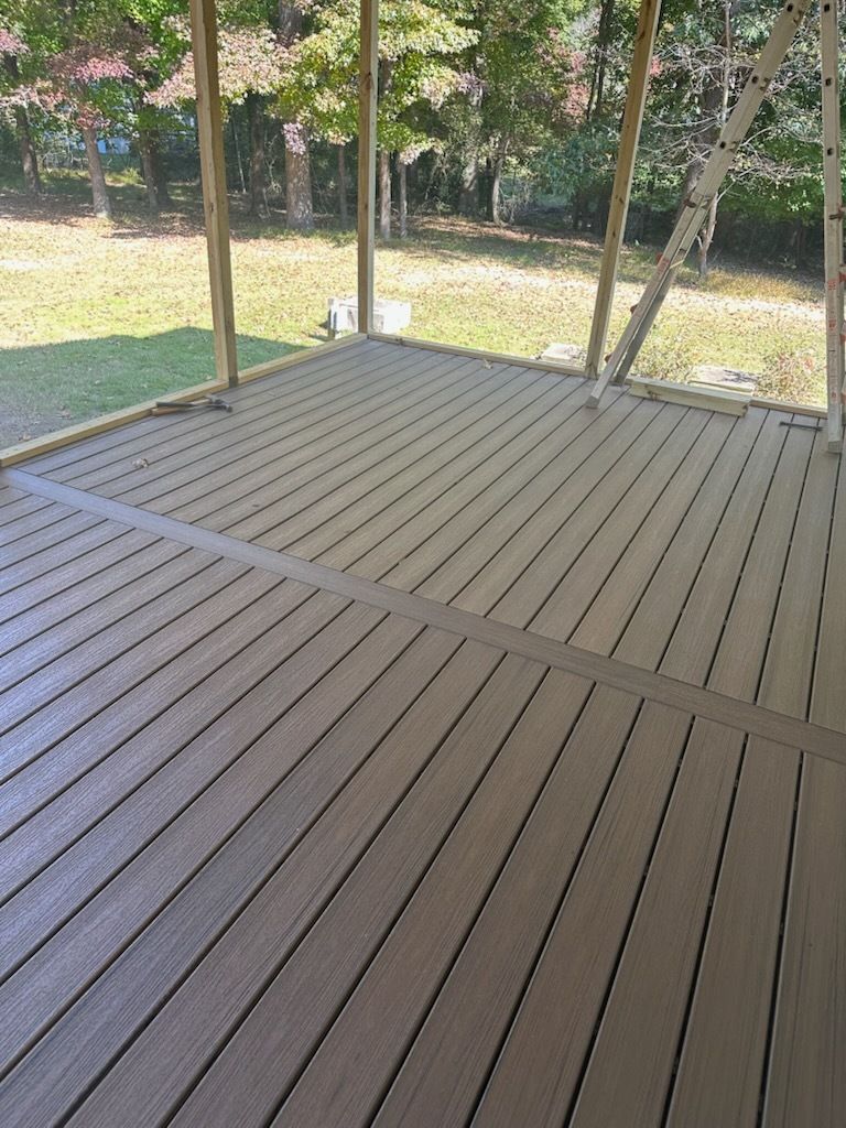 Newly constructed composite deck, brown boards, under a screened porch.