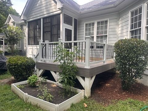Back deck with white railing and dark wood flooring; raised garden bed in front.