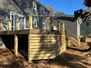 A wooden deck is sitting in front of a house.