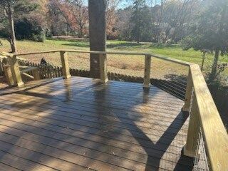 A wooden deck with a fence around it and a view of a field.