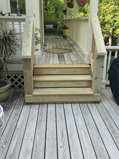 Wooden deck with three steps leading to a porch. Light-colored wood with railings.