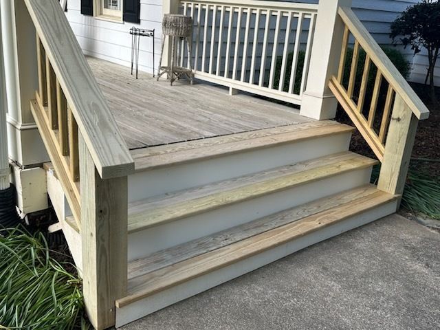 Wooden porch steps with white trim and railings.