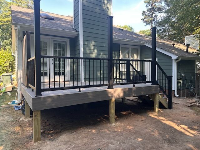 A newly constructed deck with black railings and posts, attached to a house with a green exterior.