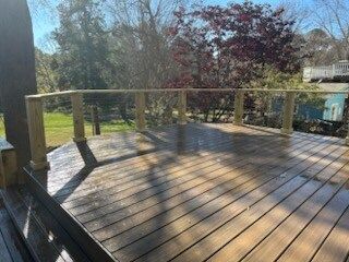 A wooden deck with a wooden railing and trees in the background.