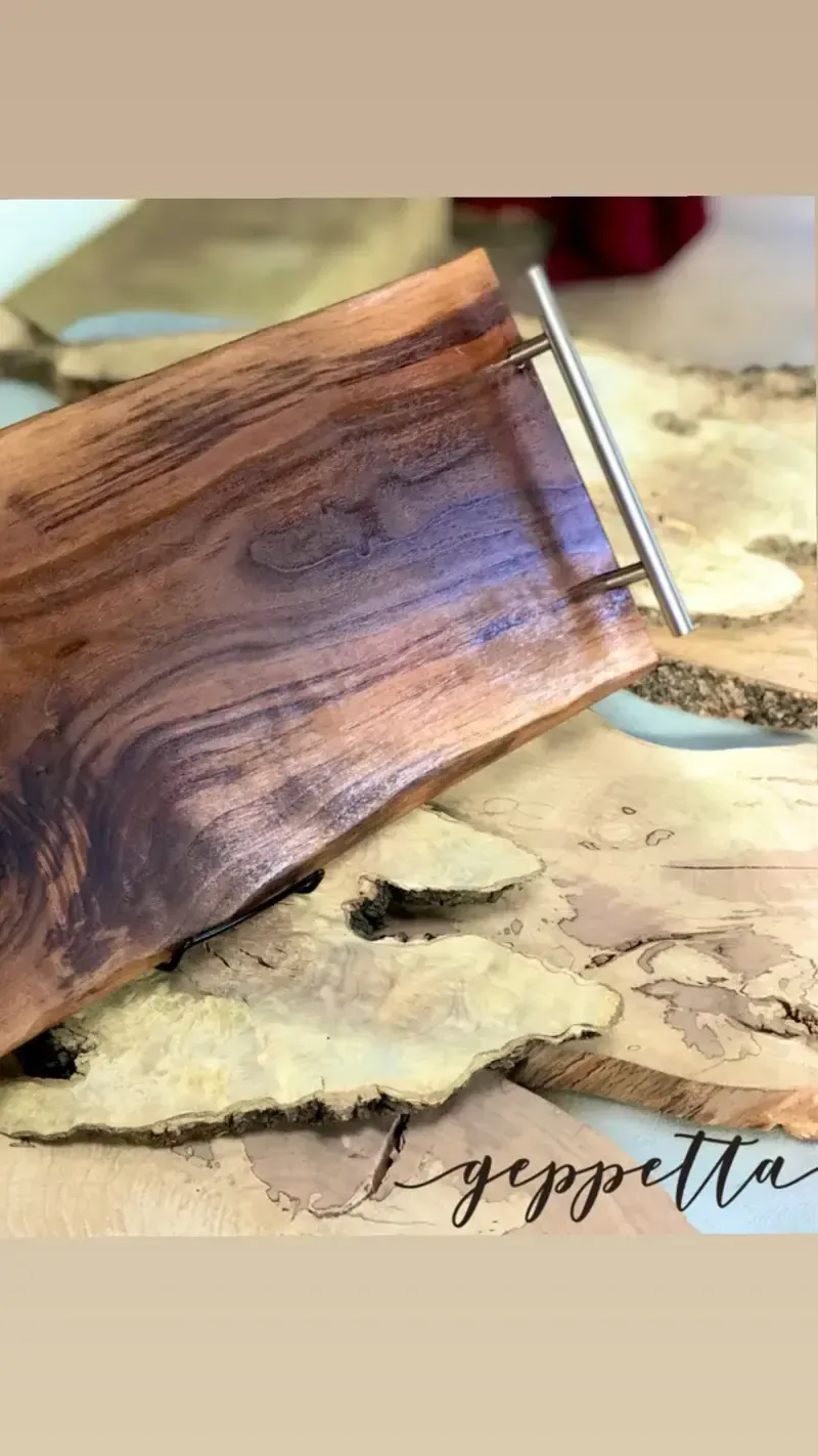 A wooden tray with a metal handle is sitting on top of a piece of wood.