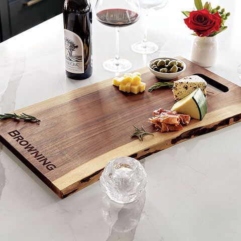 A wooden cutting board with a bottle of wine , cheese , and olives on it.