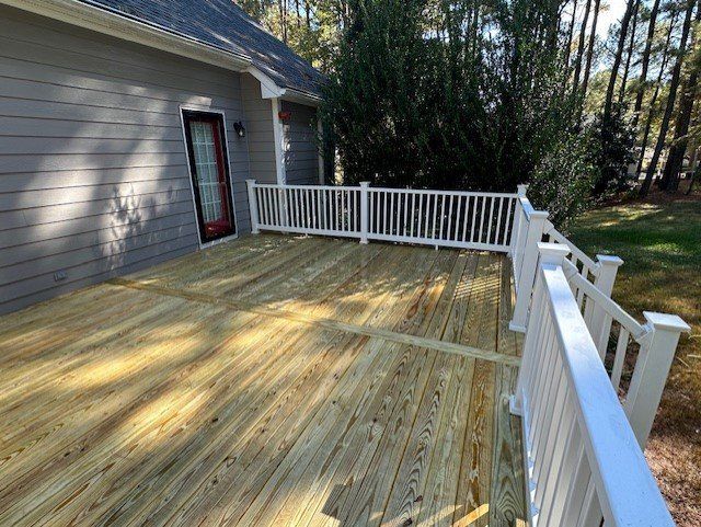 A wooden deck with a white railing in front of a house.