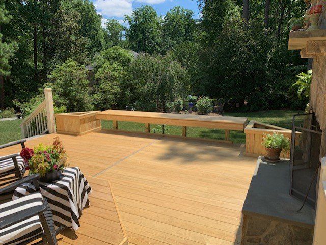 There is a wooden deck with a bench and chairs on it.