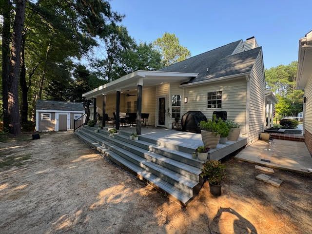 The back of a house with a large porch and stairs leading up to it.