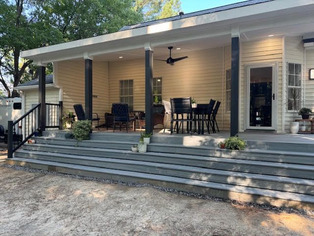 A house with a large porch with a table and chairs on it.