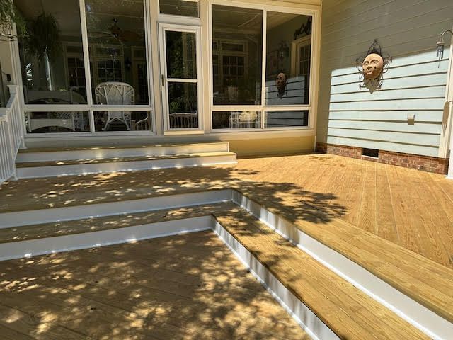 A wooden deck with stairs leading up to a screened in porch
