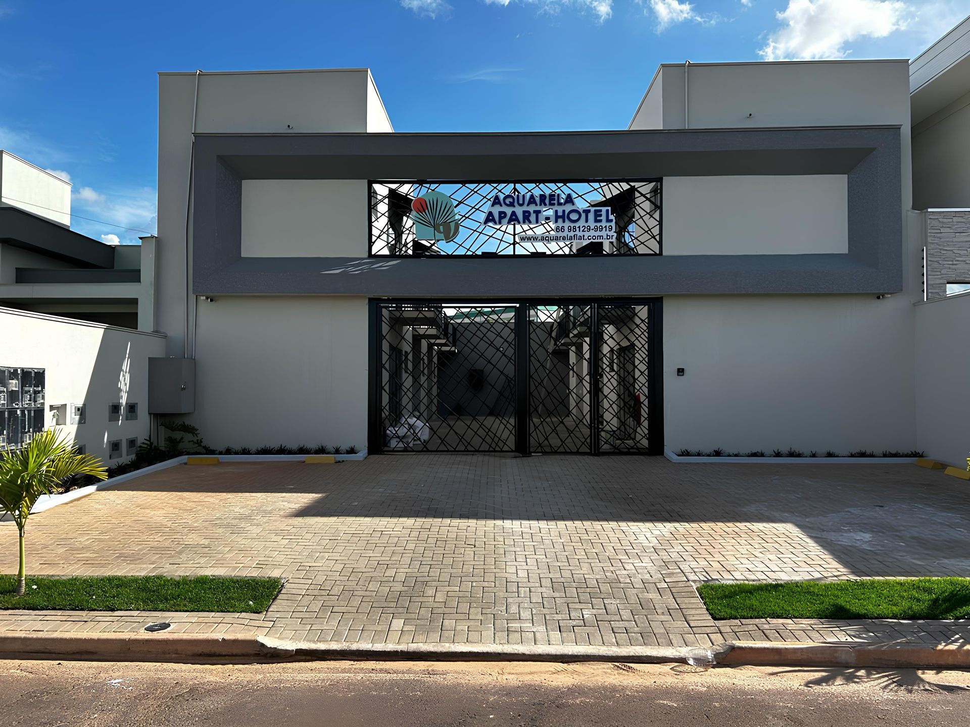 Fachada do hotel com portão preto, detalhes em cinza e uma placa. O nome "AQUARA APART-HOTEL" está visível.