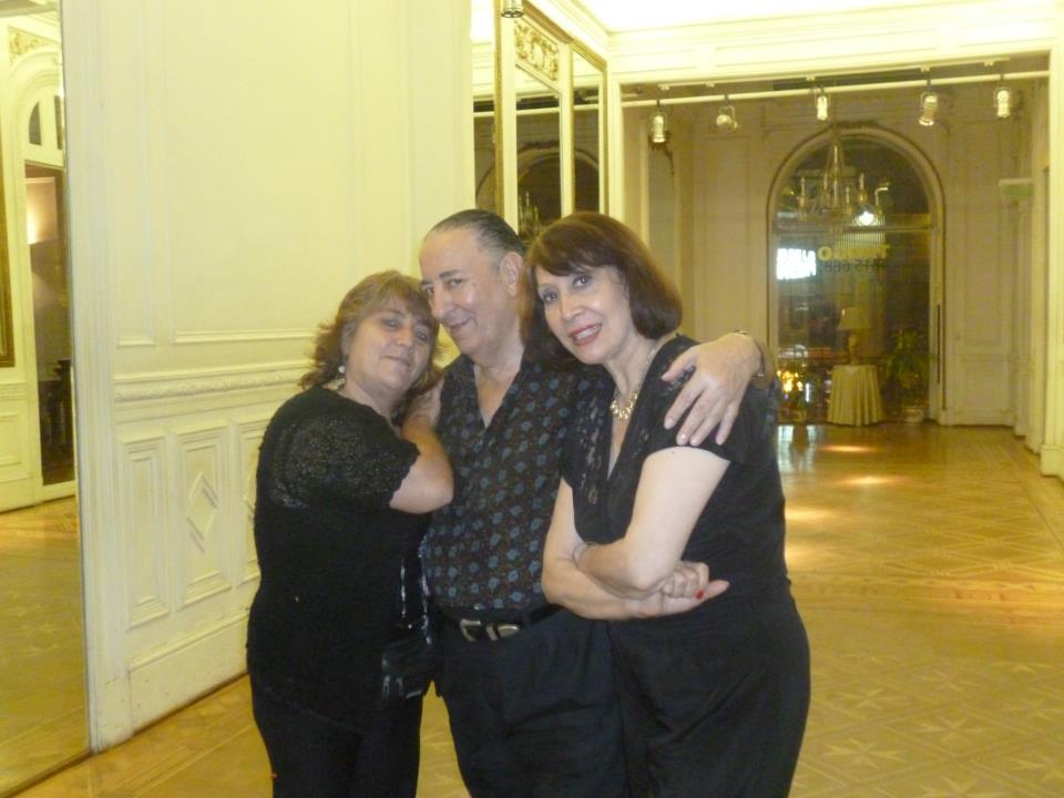 Tres personas, abrazadas, posan en una habitación grande y elegante.