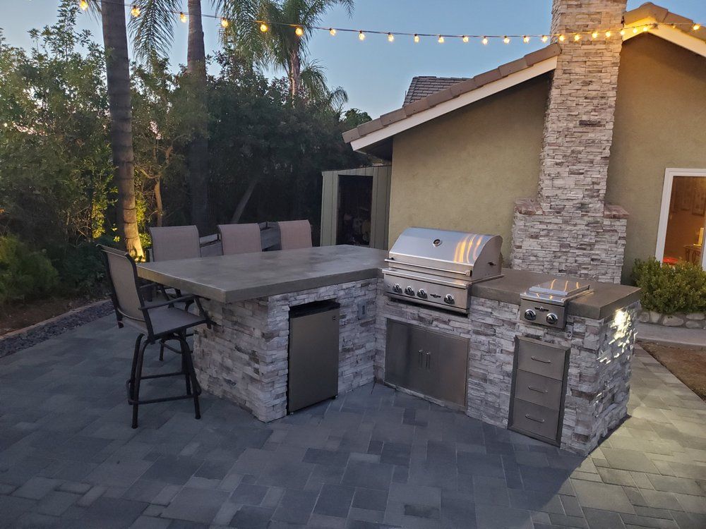 There is a grill and a table in the backyard of a house.