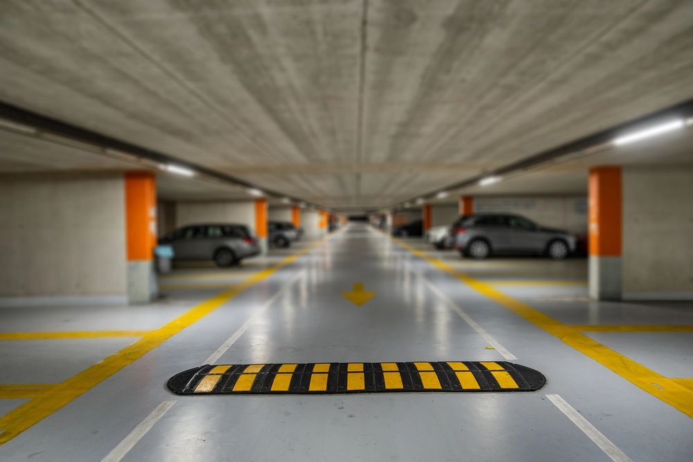 Speed bump in an underground parking garage with cars parked on either side.