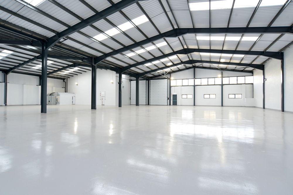 Empty warehouse interior with a gray, glossy floor and white walls.