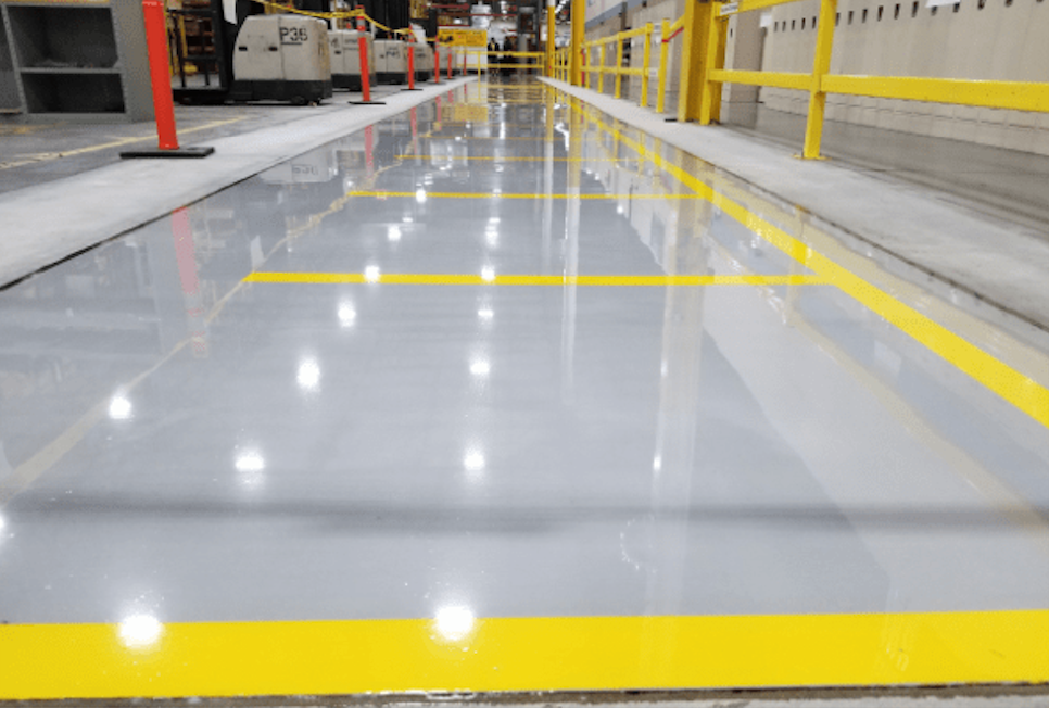 Entrance to a building with a red stanchion barrier, yellow tactile paving, and automatic doors.