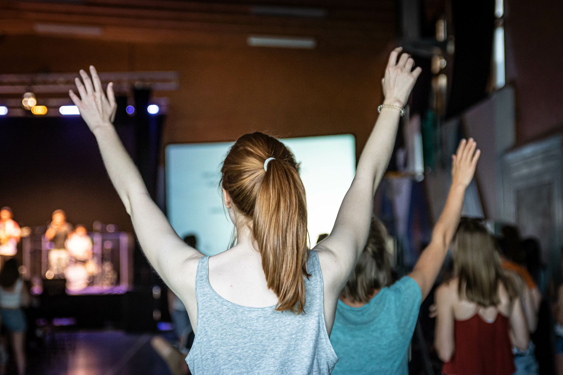 A group of people are raising their hands in the air at a concert.