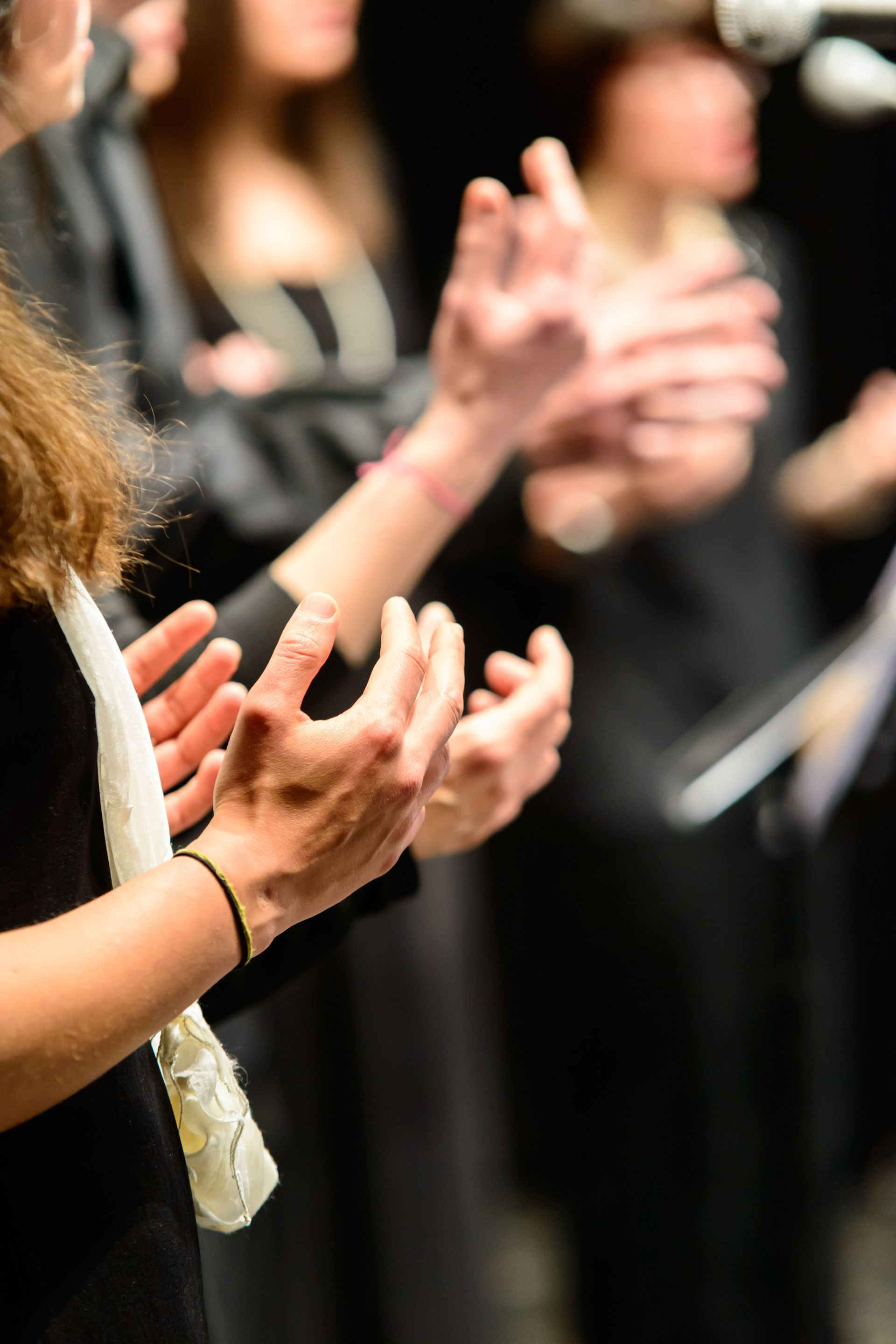 A group of people are clapping their hands in a choir.