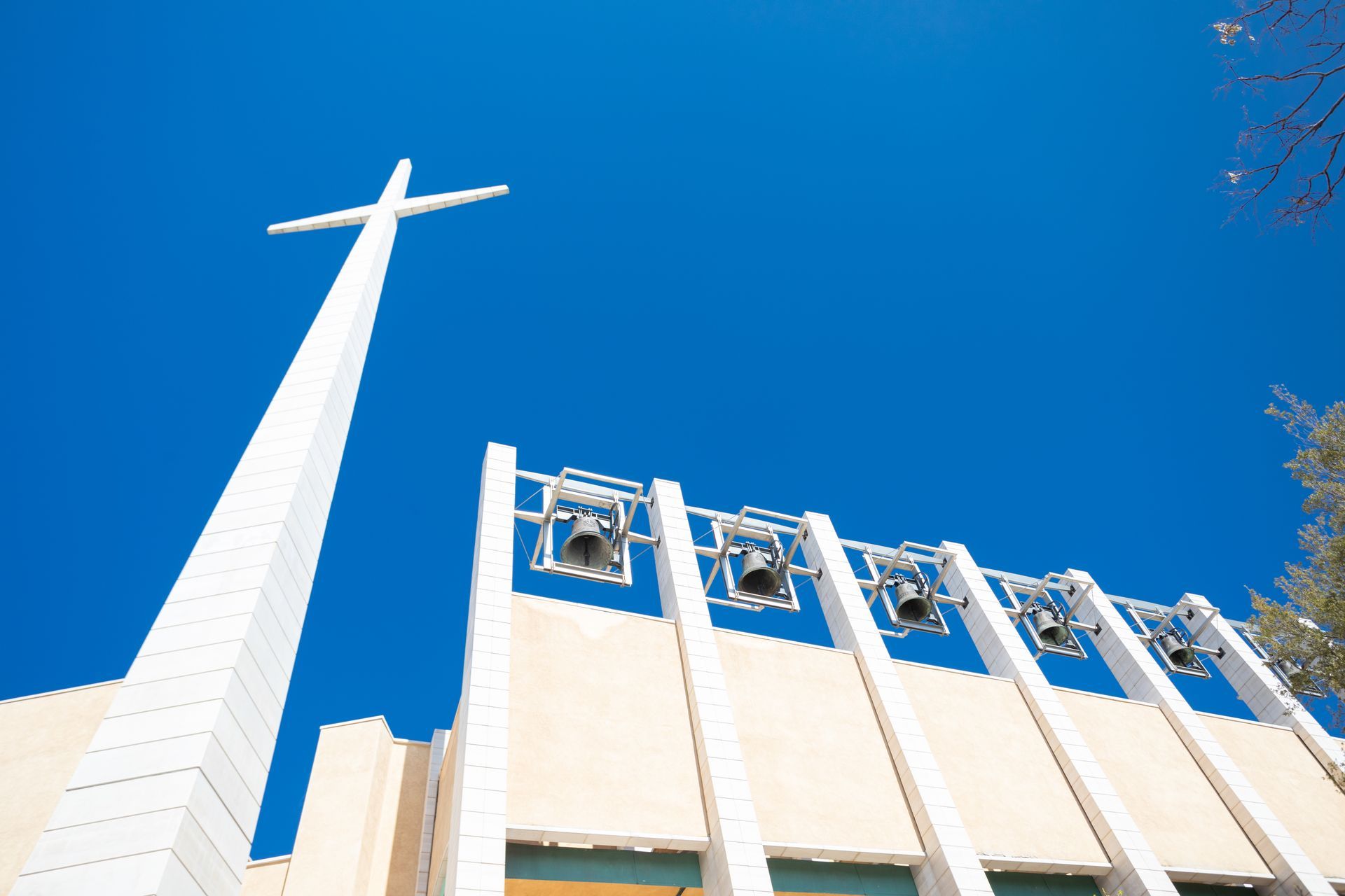 Looking up at a church with a cross and bells
