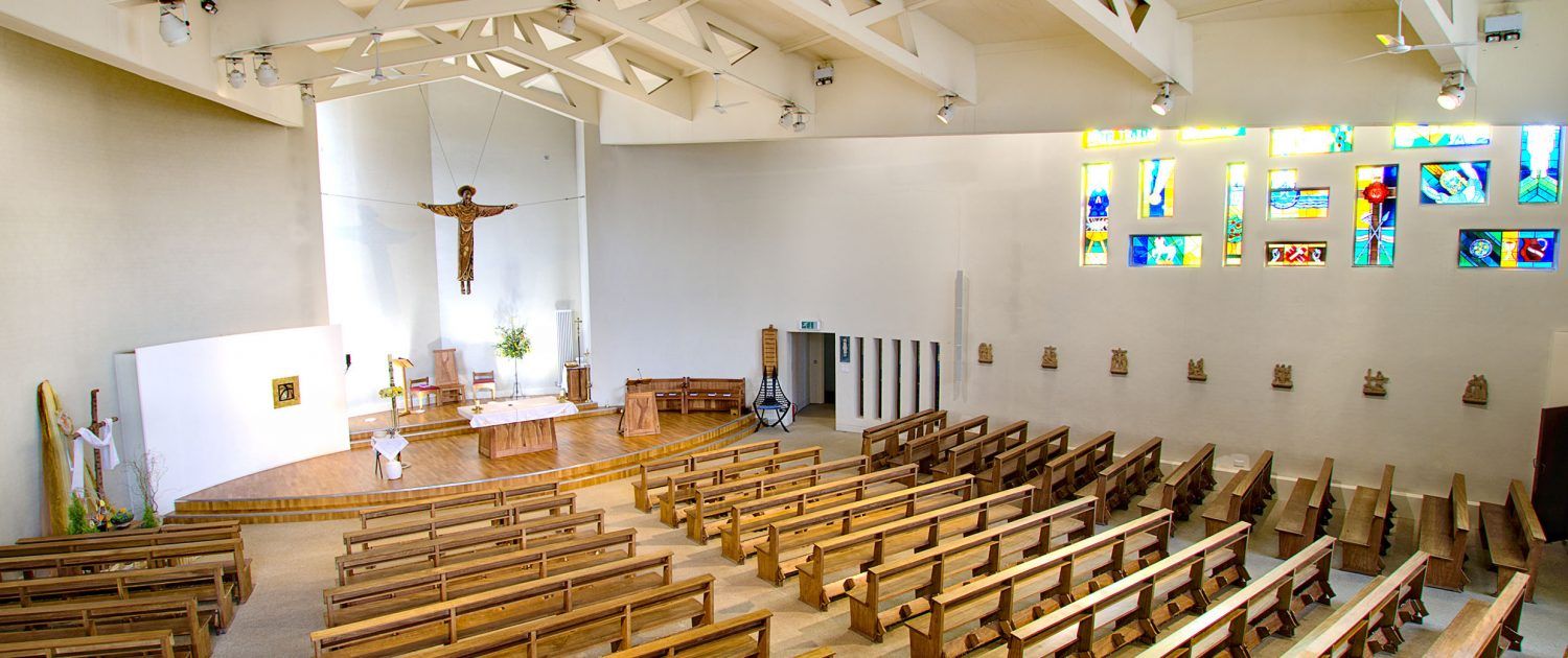 A church with rows of wooden benches and stained glass windows