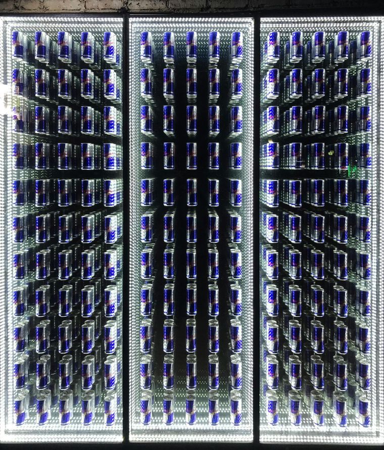 A display of red bull cans in a glass case