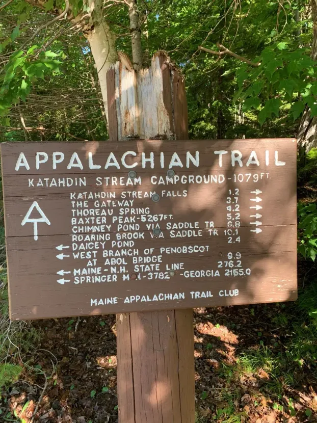 Signpost for the Appalachian Trail. Shows distances to various points. Brown, weathered wood with white lettering.