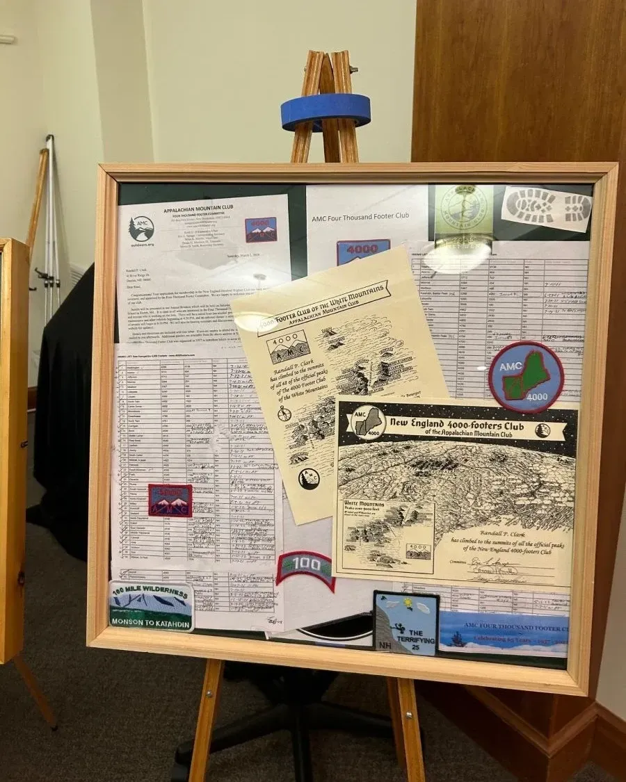 Display board with documents, maps, and patches, mounted on a wooden easel.