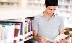 Teenager in library reading a book