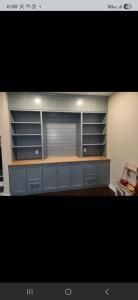 Built-in blue cabinets and shelves with a wood countertop in a recessed wall niche.