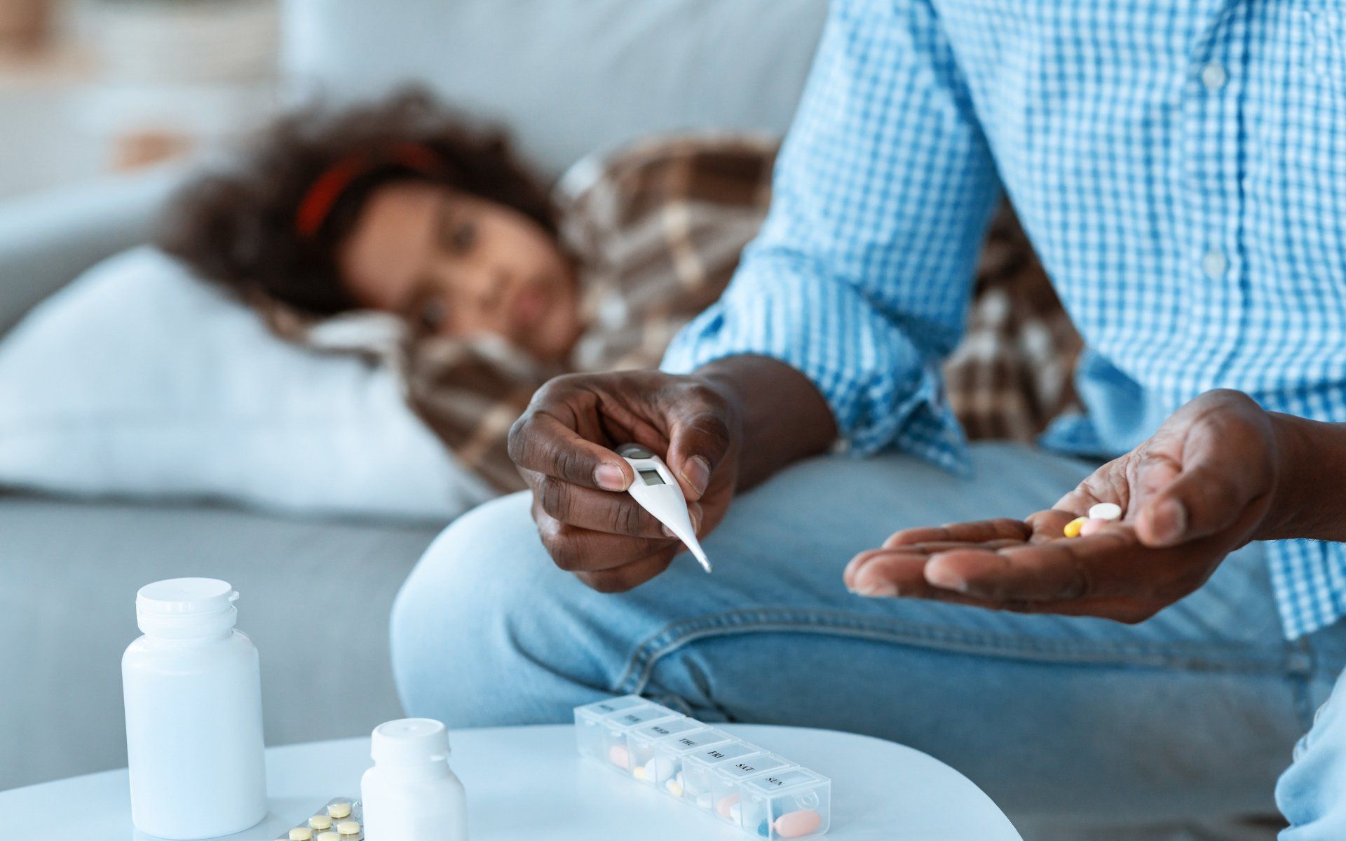 a man is holding a thermometer and a child is laying on a couch .