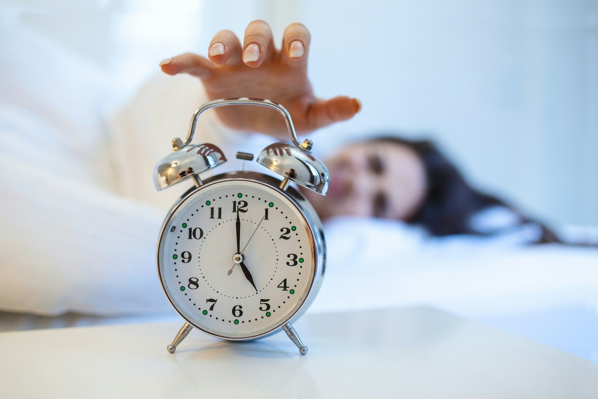 woman with sleep apnea reaching for alarm clock