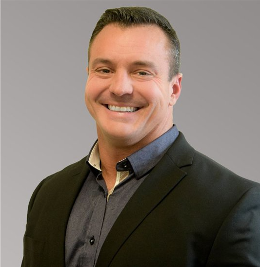 A man in a suit and blue shirt is smiling for the camera