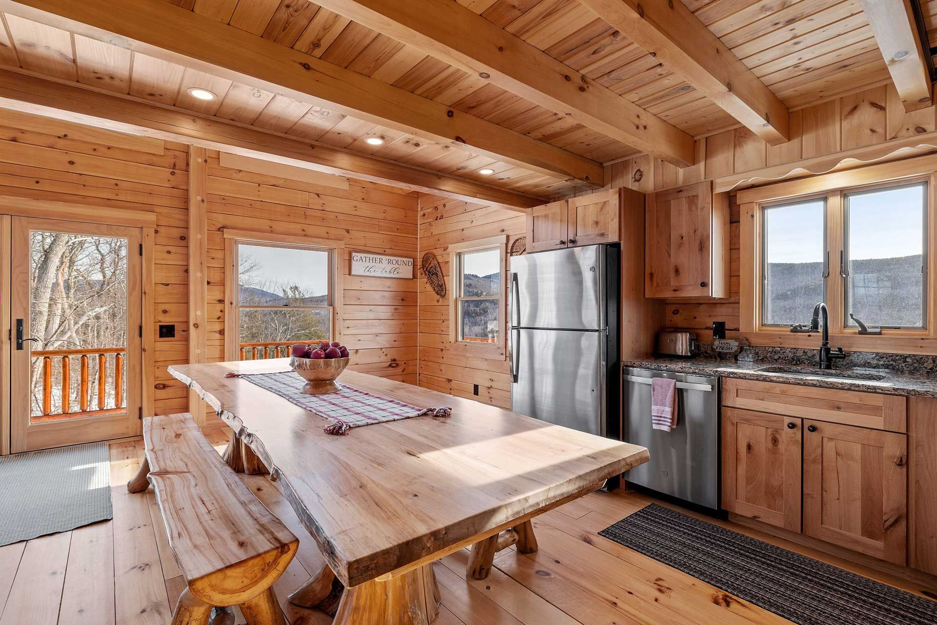 A kitchen in a log cabin with a large wooden table and benches.