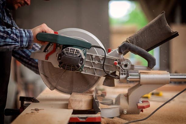 Close-up of a carpenter saw cutting a log of wood, being handled by a man in flannel shirt