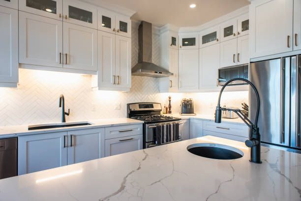 Modern kitchen with white cabinets, stainless appliances, and marble countertops.