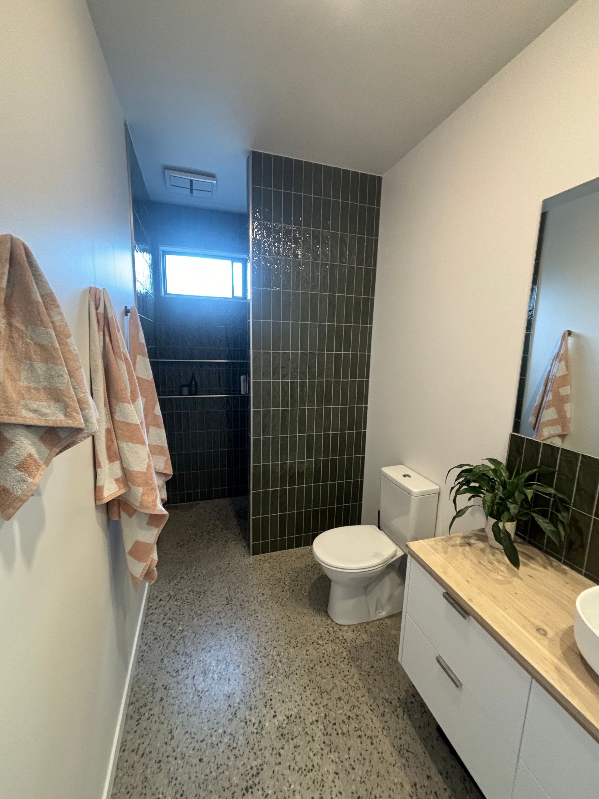 A bathroom with a toilet , sink and mirror.