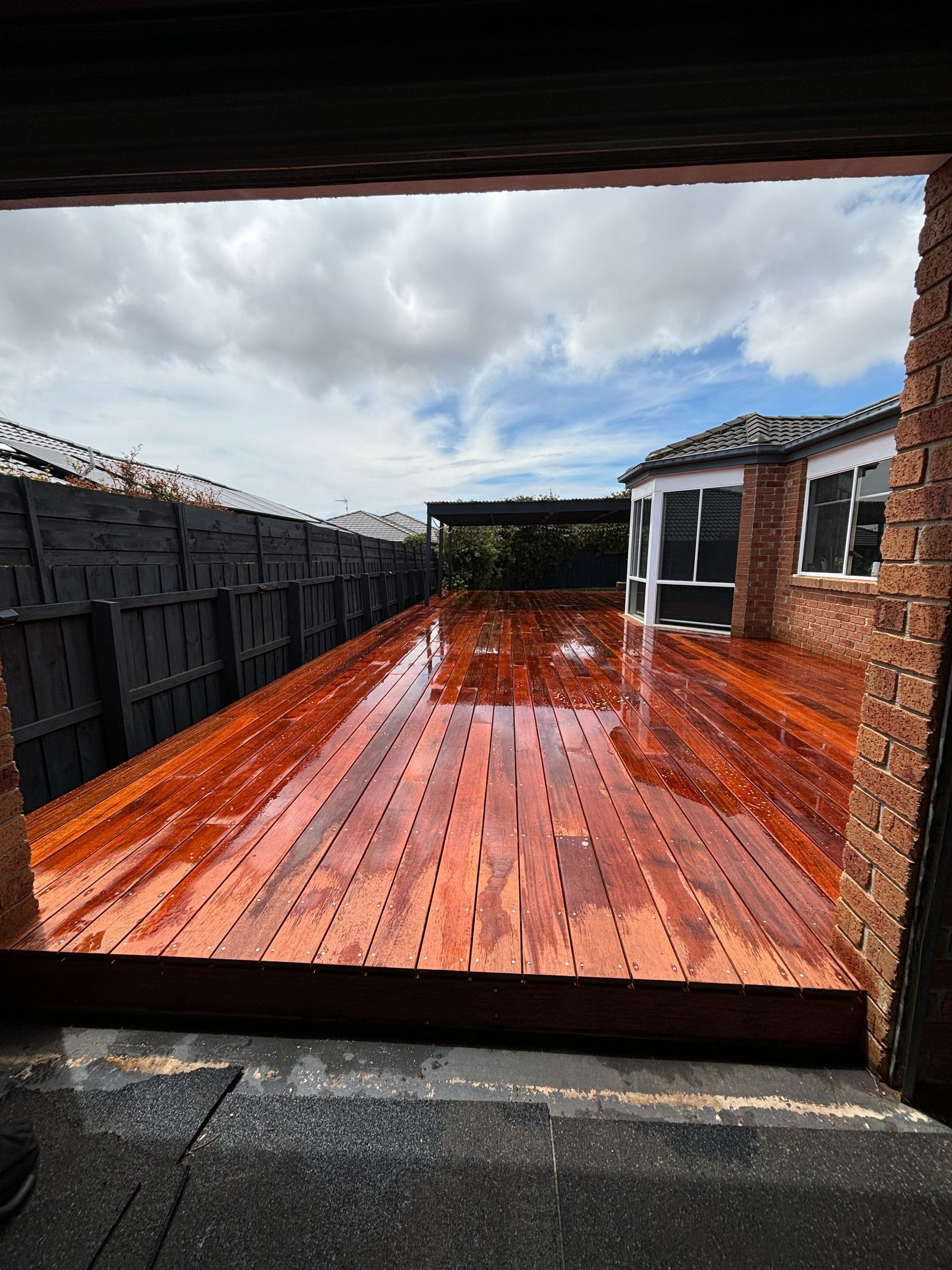 A large wooden deck is sitting in the backyard of a house.