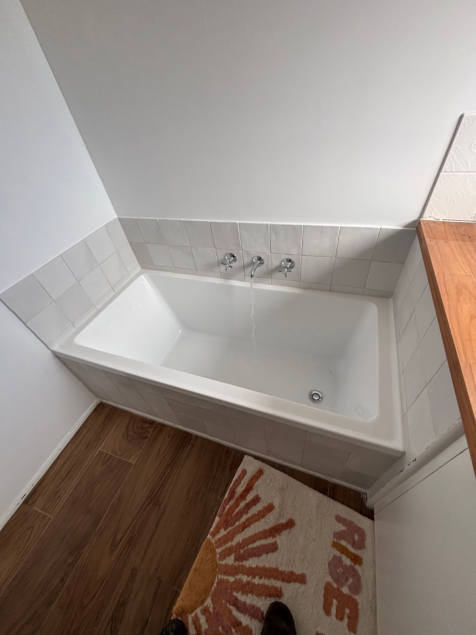 A bathroom with a bathtub and a rug on the floor.