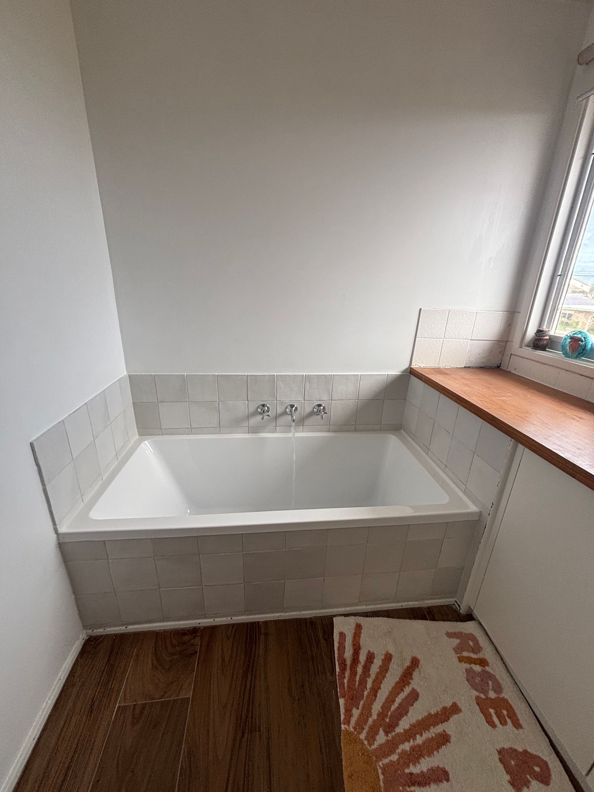A bathroom with a bathtub and a window.