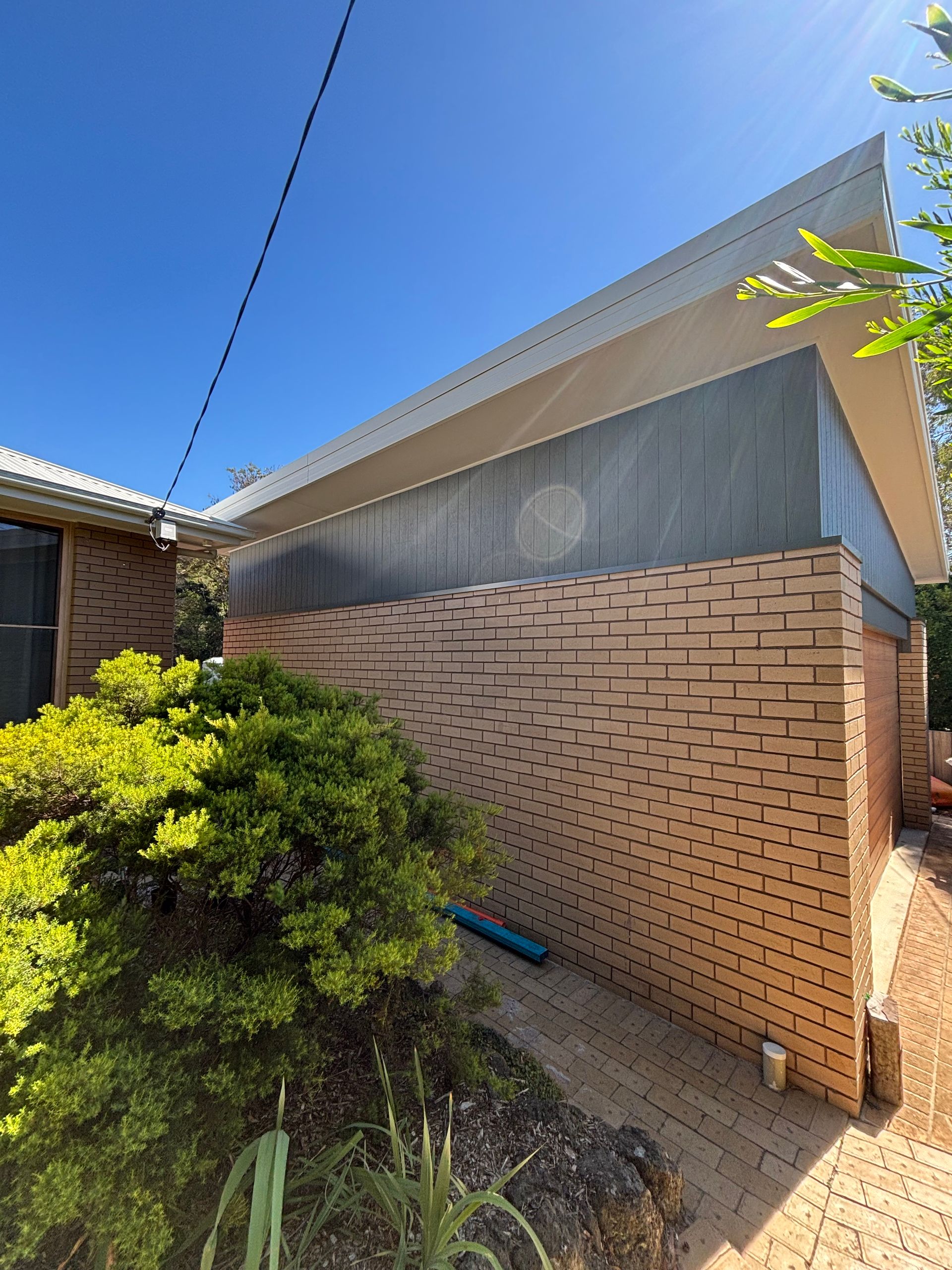 A brick building with a roof and a blue sky in the background.