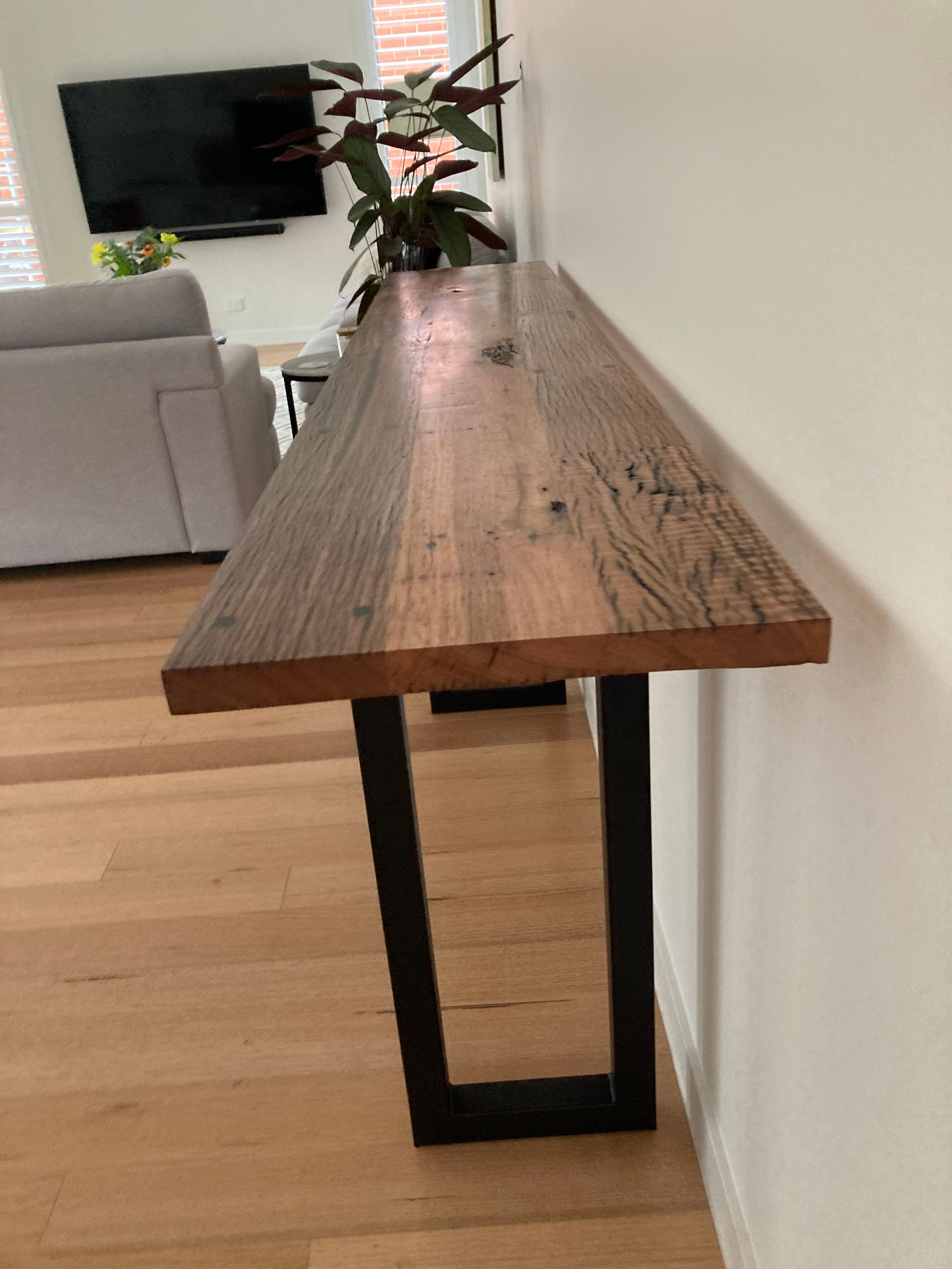 A long wooden table with metal legs in a living room