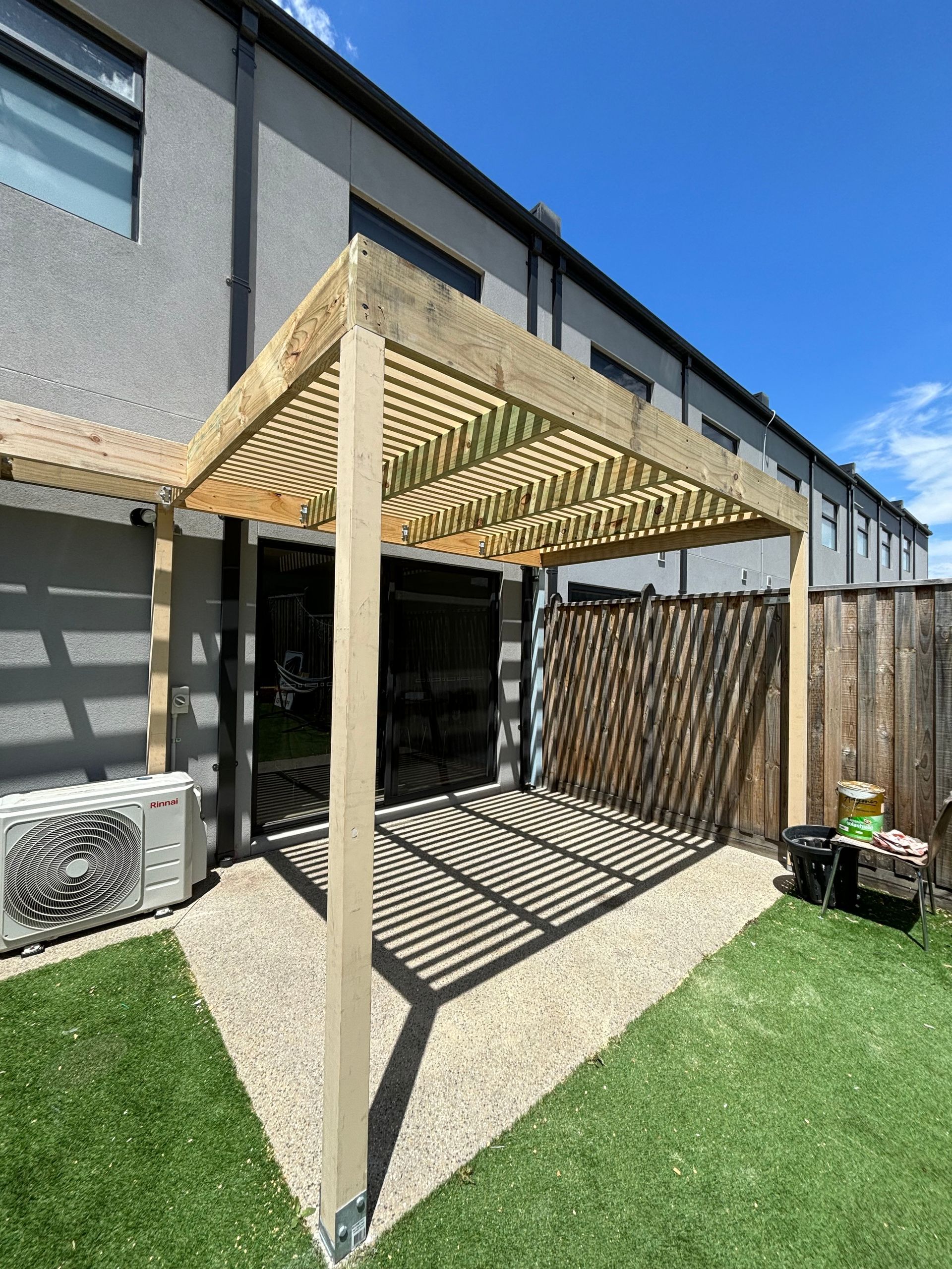 A wooden pergola is sitting in the backyard of a house.