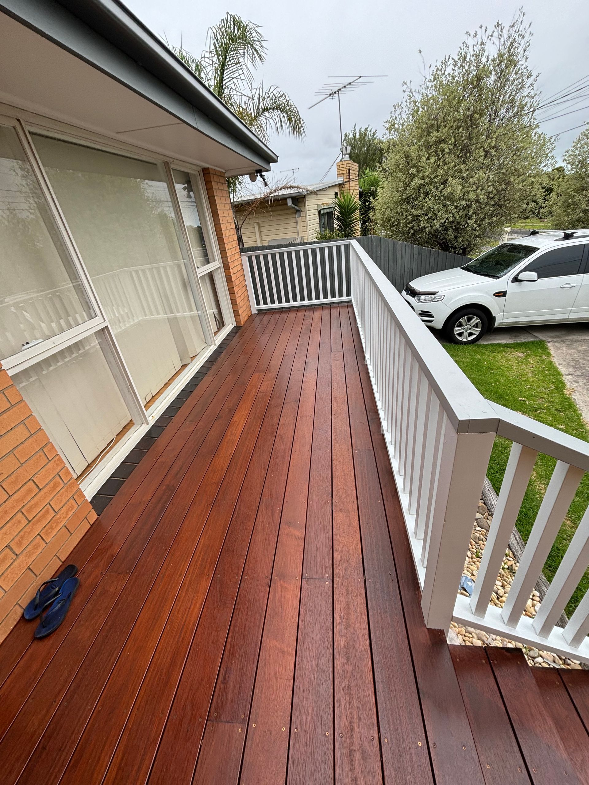 A wooden deck with a white railing is in front of a house.