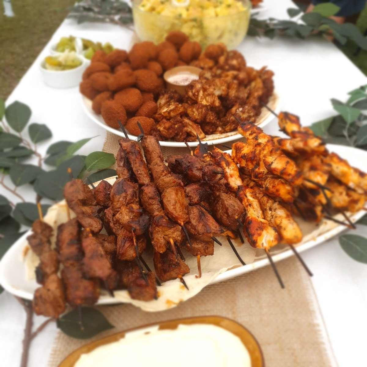 A Spread of Grilled Meat Skewers and Other Appetizers on A White Table, Outside — The Habibiz Catering In Wingham, NSW